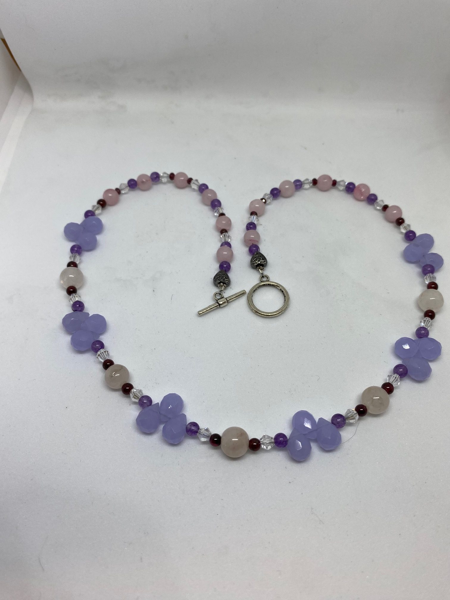 Violet Chalcedony, Rose Quartz, Amethyst, and Garnet Necklace This necklace promotes emotional stability, prosperity, and divine connection. 